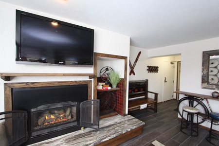 A cozy living room features a mounted TV above a fireplace,  with modern decor