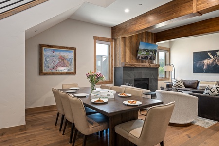 - Share meals at the elegant dining table set for eight, ideal for families and groups - Enjoy fireside ambiance with a mounted TV above the rustic stone fireplace - Large windows brighten the room while offering scenic outdoor views