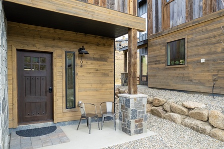 - Outdoor entryway with wood siding and modern stone accents for charm   - Patio chairs offer a quiet spot to enjoy morning coffee or evening air   - Welcoming design blends rustic touches with a stylish mountain feel