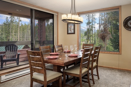 Dining room with a wooden table set for six, and views outside the large windows