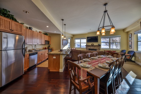 Spacious open-concept kitchen and dining area with wooden cabinets, stainless steel appliances, granite countertops, a large dining table