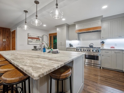 Gleesome Inn- Kitchen island with a perspective of the full kitchen and stove appliance