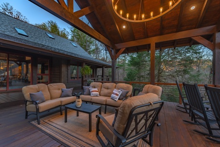 River Joy Lodge- Entry Level Deck Covered Fireplace Seating Area at Dusk