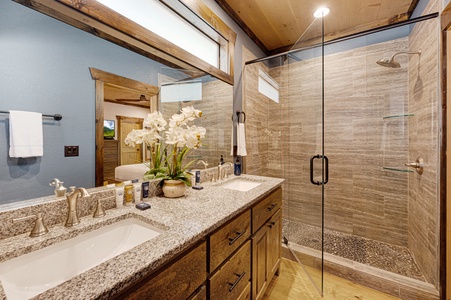Mountain Echoes- Entry level private bathroom with double vanity sink, and walk in shower