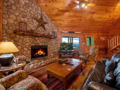 Aska Bliss- Living room area with a large fireplace TV, and cabin decor