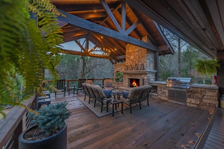 River Joy Lodge- Entry Level Deck Covered Fireplace Seating Area at Dusk