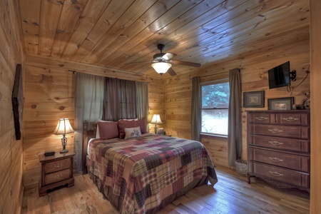 Aska Lodge- main level queen bedroom with antique style furniture and a mounted TV