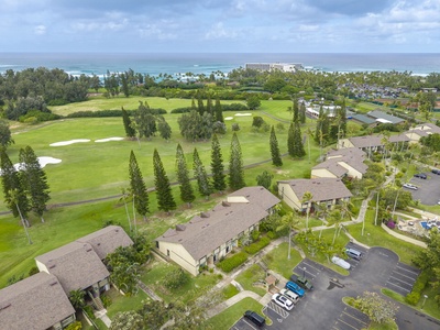 Aerial view of the vacation rental property featuring lush golf course surroundings, tropical landscaping, and oceanfront location with convenient parking facilities.