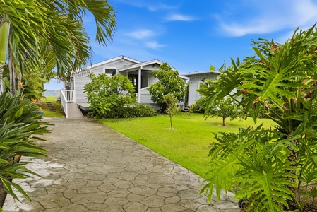 A charming vacation home framed by lush tropical gardens and swaying palms. A welcoming path leads to your private retreat beneath sunny skies.
