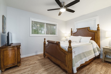 Rest easy in your elegant bedroom featuring beautiful wood furnishings, crisp linens, and refreshing ceiling fan for ultimate comfort.