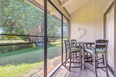 Your private screened patio invites morning coffee with garden views, featuring a high-top table perfect for intimate meals surrounded by lush greenery.