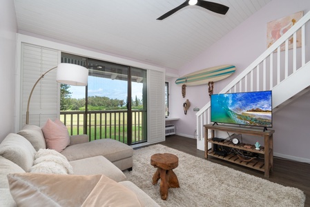 Relax in your cozy living space with soft seating, a ceiling fan, and sliding doors opening to lush green views. The surf-inspired decor and warm wood accents create a breezy, coastal vibe perfect for unwinding after a day of adventure.