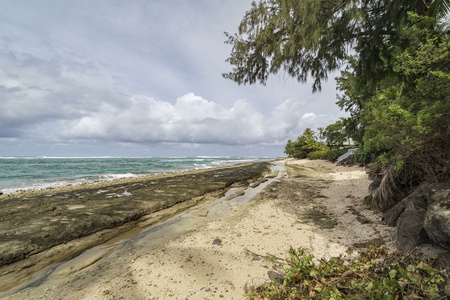 Pristine tropical beach with coral rock formations and lush vegetation creating a secluded paradise setting.