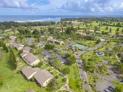 Aerial view of a tropical resort community with tennis courts, swimming pools, and lush golf course fairways stretching toward the ocean.