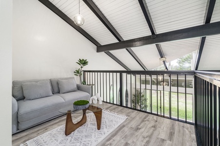 Your cozy loft seating area features exposed beams and natural light, perfect for morning coffee or evening relaxation with garden views.