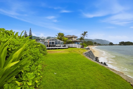 Beachfront property nestled between lush tropical gardens and pristine sandy shores, with mountain views framing the peaceful coastal setting.