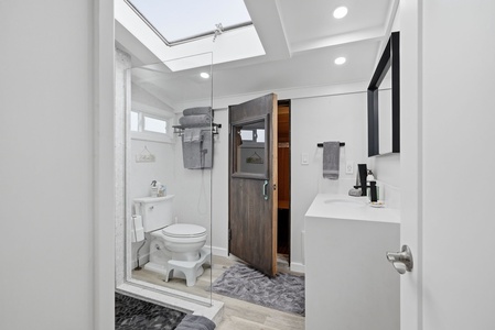 Your private bathroom features a glass-enclosed shower, skylight, and stylish modern finishes that create a bright, spa-like retreat perfect for unwinding after a day of exploring.