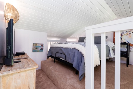 Unwind in your private sleeping loft, where two cozy beds await beneath charming wood-paneled ceilings and soft, inviting linens beckon restful nights.