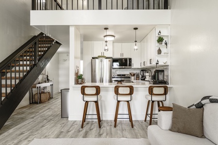 Your modern open-concept space blends style and function with sleek white kitchen, breakfast bar, and stylish staircase.