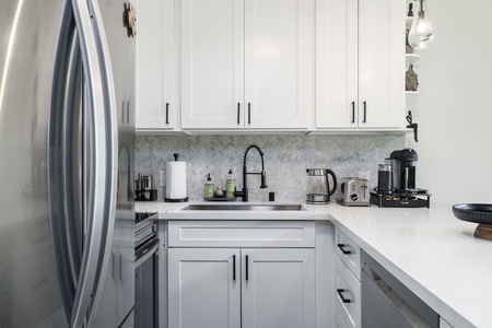 Your bright, modern kitchen features sleek white cabinets, gleaming countertops, and all the appliances you need for creating memorable meals during your stay.