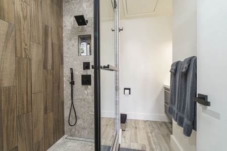 Step into your sleek modern bathroom with a luxurious walk-in shower featuring rainfall fixtures and warm wood-grain tile accents.