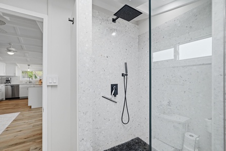 Step into your modern spa-like shower with sleek terrazzo tiles, rainfall showerhead, and handheld wand. The frameless glass and stylish black fixtures create a luxurious retreat after your island adventures.
