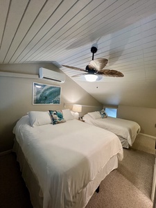 You'll rest easy in this coastal-themed bedroom featuring two plush beds dressed in crisp white linens, a tropical ceiling fan, and air conditioning to keep you cool after a day of adventures.