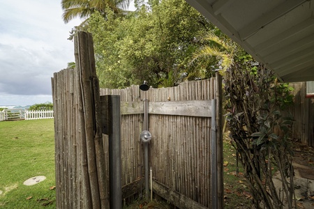 Step into your private outdoor shower, surrounded by lush tropical palms and bamboo fencing for complete privacy.