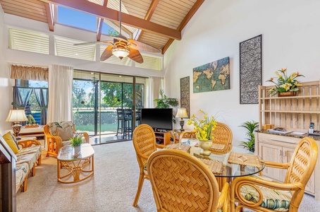Unwind in your bright, tropical-inspired living space with soaring ceilings, warm rattan furniture, and peaceful garden views from the glass doors.