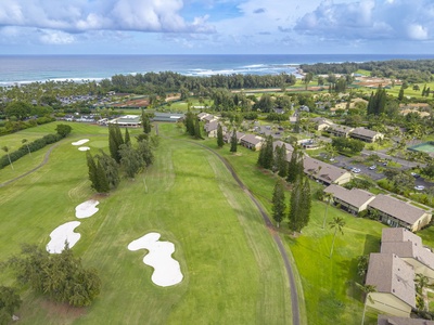 Aerial view showcasing pristine Ritz-Carlton golf course fairways with sand bunkers, surrounded by tropical vegetation and ocean views in the distance.