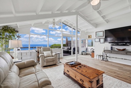 Bright, airy living room with vaulted ceilings, plush seating, and stunning ocean views through floor-to-ceiling windows—your perfect space to unwind and soak in the coastal beauty.