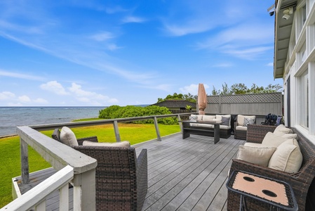 A spacious waterfront deck overlooks tranquil waters and lush lawns, offering comfortable outdoor seating where you can unwind, enjoy refreshing breezes, and soak in serene views.