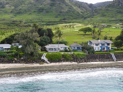 Beachfront home nestled between rolling green hills and pristine coastline, offering direct beach access and tropical island serenity.
