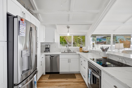 Your bright, fully-equipped kitchen awaits—marble counters, stainless appliances, and tropical views streaming through the windows. Perfect for preparing meals and starting your day right.