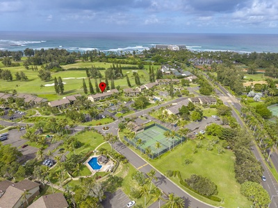 Aerial view showcasing the resort's prime location between championship golf course and pristine beach, with tennis courts and pool facilities visible.