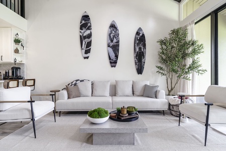 Sink into plush seating in your stylish living room, where surfboard art and natural light create the perfect coastal retreat atmosphere.