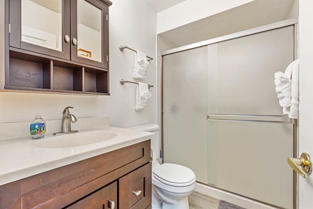 Your private bathroom features a sleek shower with frosted glass doors and ample storage for your essentials.