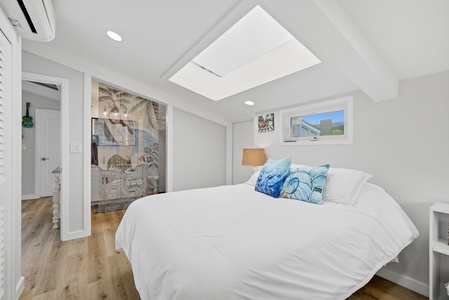 Your bright, coastal-inspired bedroom features a plush bed, natural light from a skylight, and ocean-themed décor to help you unwind in complete comfort.