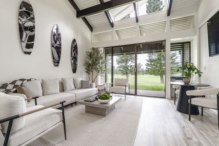 Unwind in your bright living space with soaring beamed ceilings, plush seating, and peaceful garden views through floor-to-ceiling windows.