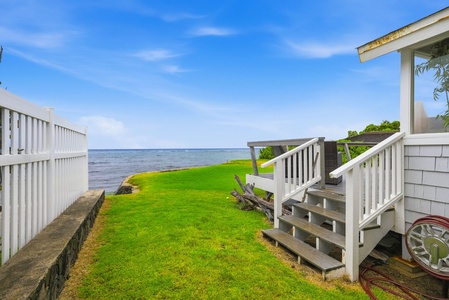 The property features a private lawn leading directly to the waterfront, with coastal views stretching across the horizon, perfect for seaside relaxation.