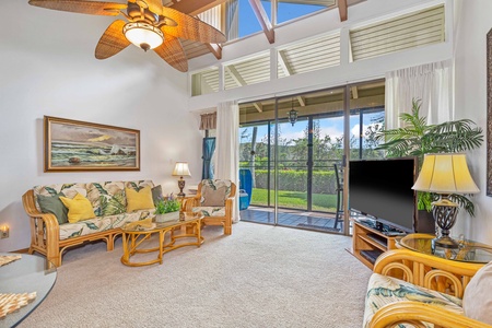 Relax in your tropical-themed living room with comfortable rattan furniture, where natural light streams through floor-to-ceiling windows overlooking lush greenery.