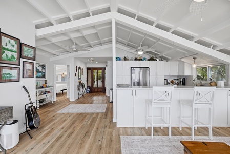 Step into an open-concept space where high coffered ceilings and tropical light create an airy sanctuary. Your kitchen island invites morning coffee, while warm wood floors lead you through bright, art-filled rooms perfect for island living.