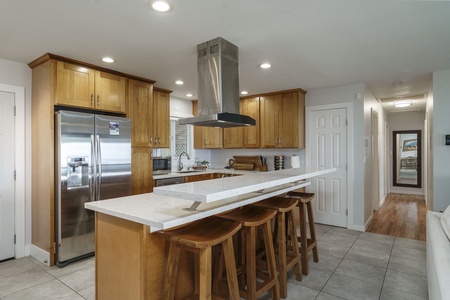 Gather around your spacious kitchen island with marble countertops and warm wood cabinetry, perfect for cooking together and casual dining.
