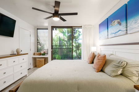 Wake up in your serene bedroom with lush tropical greenery framed by sliding glass doors. Coastal art and soft linens set the scene for peaceful mornings.
