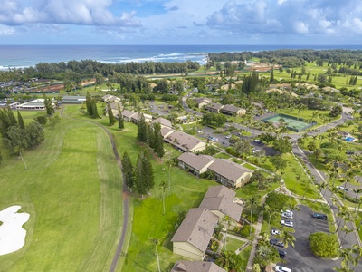 Aerial view showcases the property's prime location between championship golf course and pristine coastline, surrounded by lush tropical landscaping.