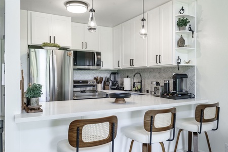 Your modern kitchen awaits with sleek white cabinetry, stainless appliances, and a spacious breakfast bar perfect for morning coffee or evening conversations.
