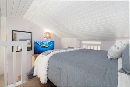 Unwind in your cozy loft bedroom where vaulted ceilings and soft lighting create a peaceful retreat after days exploring the coast.