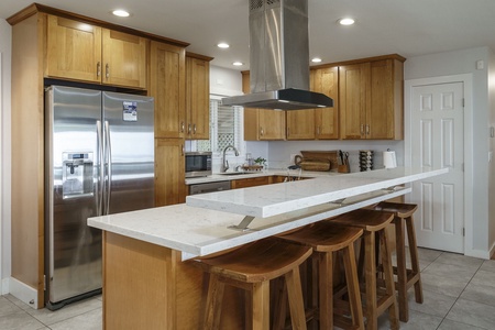 Your fully equipped kitchen features warm wood cabinetry, stainless steel appliances, and a spacious island perfect for cooking together.