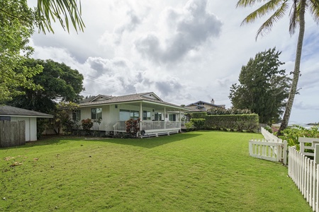 A charming single-story home with wraparound deck sits on spacious tropical grounds surrounded by lush palms and mature landscaping.