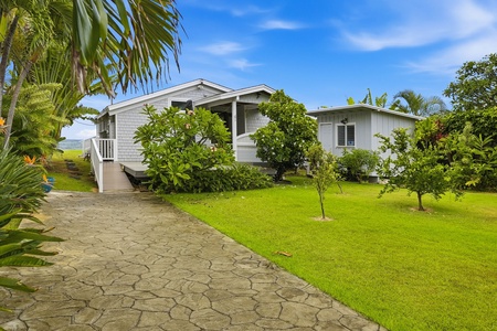 Charming tropical retreat surrounded by lush gardens and swaying palms, offering a peaceful island escape under sunny blue skies in a scenic coastal setting.